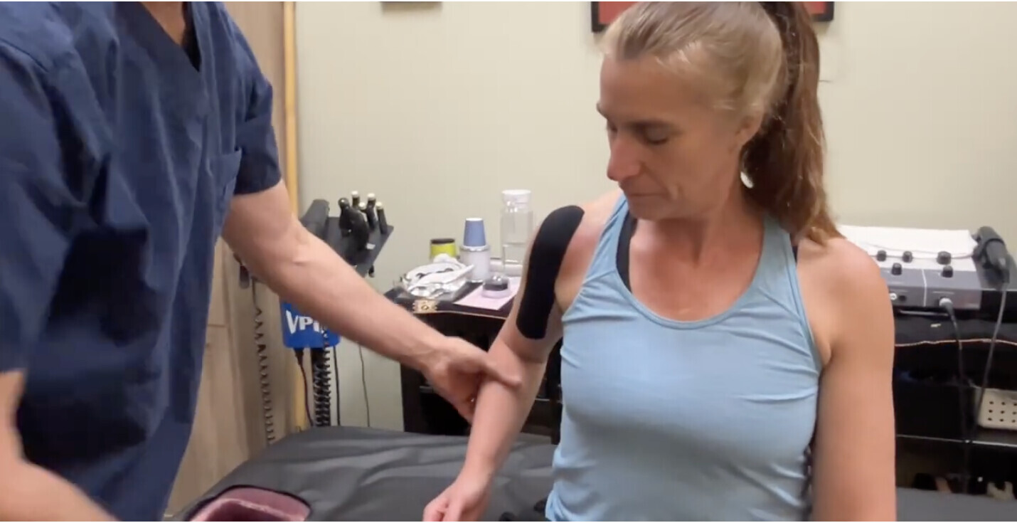 Dr Cohen is applying Kinesiology Tape to the shoulder