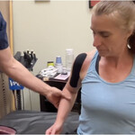 Dr Cohen is applying Kinesiology Tape to the shoulder